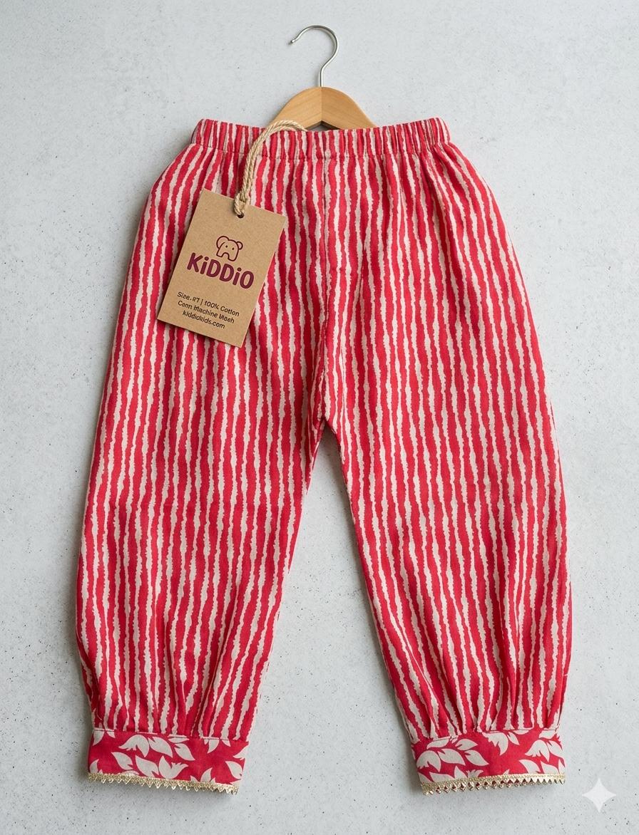 Red and white vertically striped cotton pants for toddlers, hanging on a wooden hanger with a brown paper brand tag that reads 'KIDDIO'.