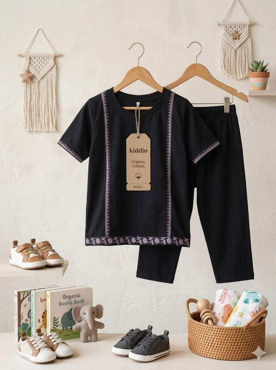 Children's black outfit with hangers, shoes, books, and a basket on a light background