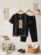 Children's black outfit with hangers, shoes, books, and a basket on a light background