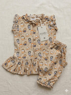 A baby girl's two-piece linen outfit set by Kiddio, featuring a ruffled sleeveless top and matching ruffled bloomers. The set is printed with a whimsical pattern of cartoon cats in orange, blue, and black on a warm beige linen background.
