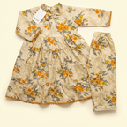 A baby girl's two-piece outfit set consisting of a long-sleeve tunic top and matching pants, featuring an orange and gray floral pattern on a beige background, laid flat on a cream-colored surface.