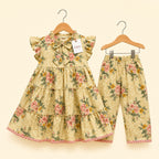A toddler girl's two-piece floral outfit set consisting of a tiered ruffle-sleeve dress and matching pants, hanging on wooden hangers against a light cream background. The set features a warm beige base with a pink, green, and yellow floral pattern.